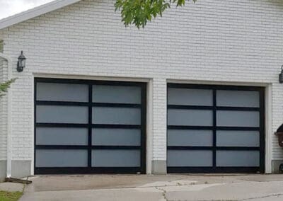 Tan brick home with glass paneled garage doors