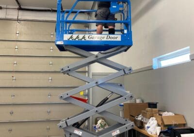 Worker from AAA Garage Door on a cherry-picker fixing garage door chain