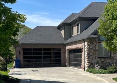 Home with stone and brick exterior as well as a glass paneled garage door