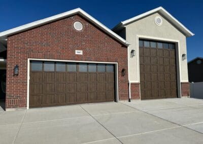 Front of workshop garage doors. Garage doors are both brown wood paneled and one is taller than the other